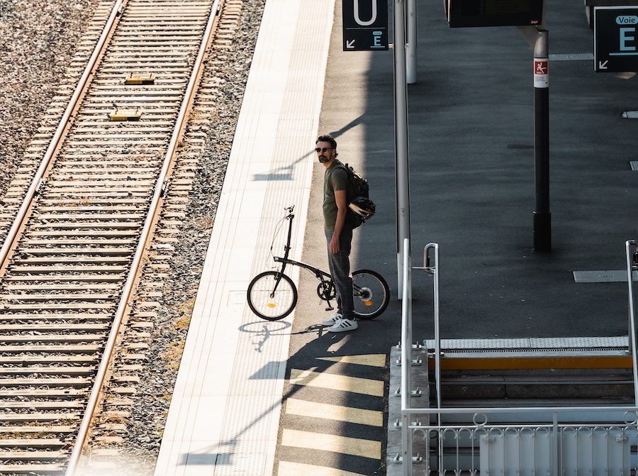 Un salarié attend le train avec son vélo de fonction pliant