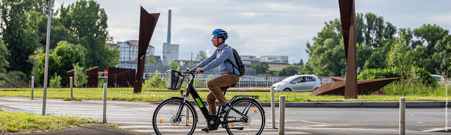 Vélotafeur heureux arrivant au travail sans transpirer grâce au VAE public Naolib