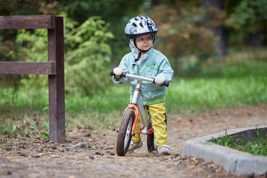 Enfant avec draisienne et casque dans un parc, apprentissage vélo 2-3 ans