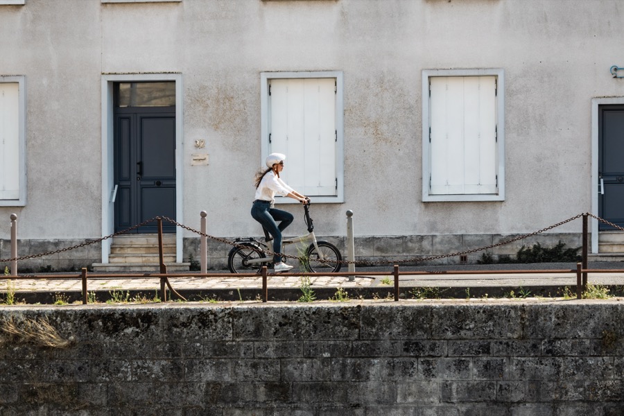 Cycliste casquée roulant confortablement sur un vélo pliant le long d un quai à La Rochelle