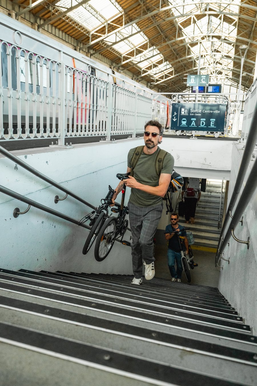 Voyageur portant son vélo pliant dans les escaliers d une gare