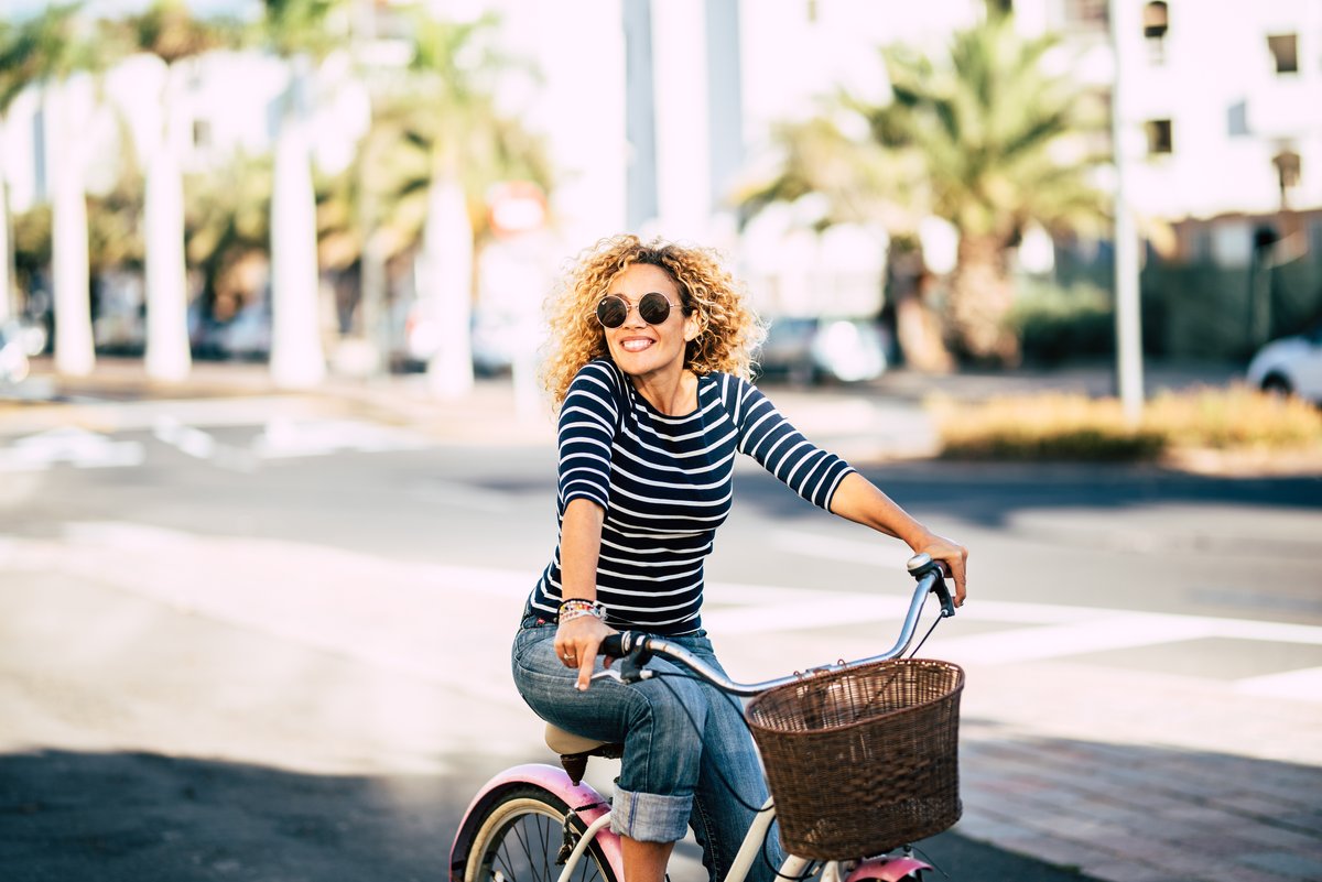 Femme à vélo en ville avec un panier vélo avant