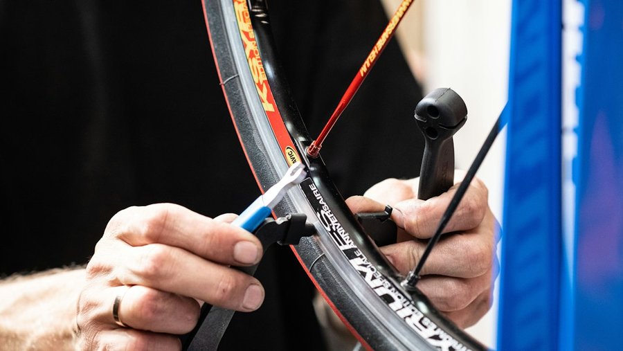 Mains démontant le pneu d'une roue de vélo avec un démonte-pneu pour inspecter la chambre à air après une crevaison