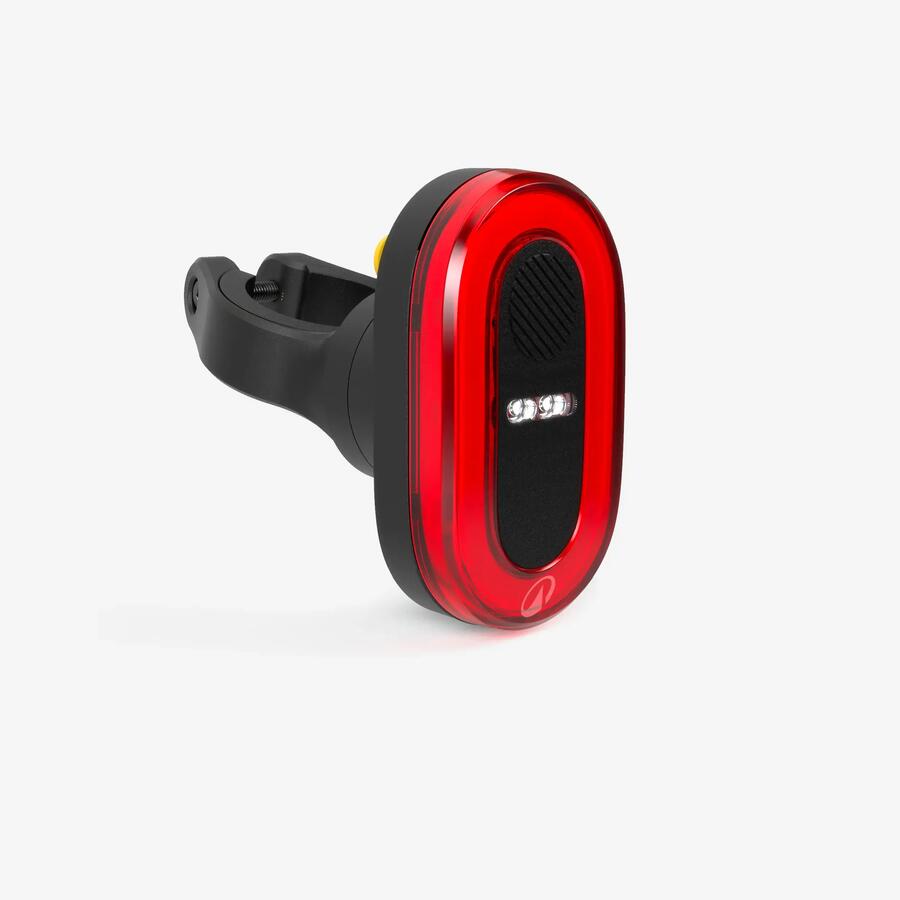 Feu arrière vélo Decathlon RL930 : boîtier rouge ovale avec sa fixation, capteur de décélération intégré