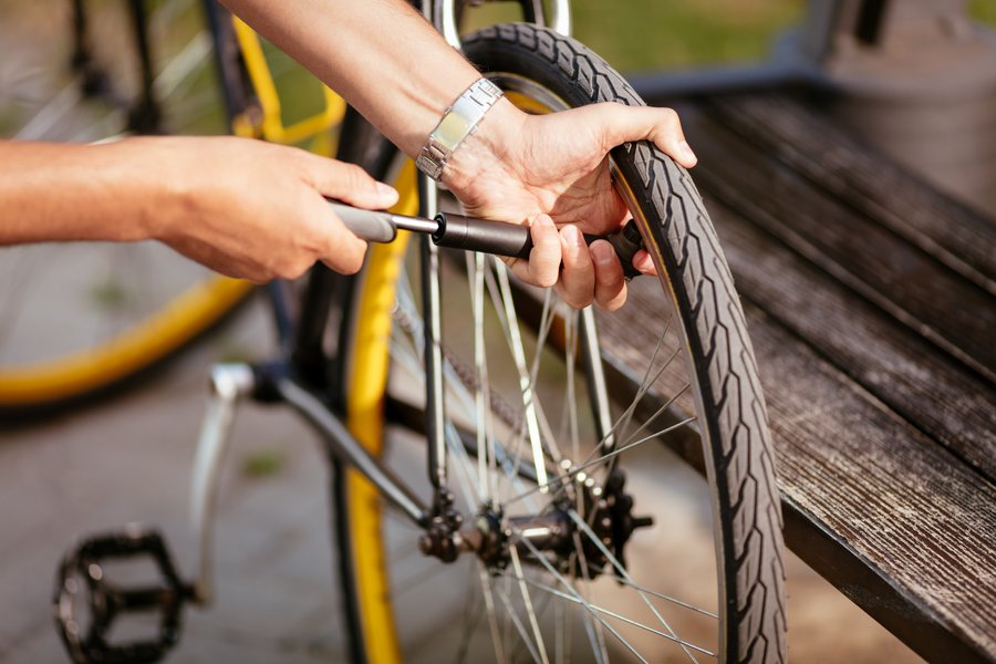 Mains gonflant la roue d'un vélo avec une mini-pompe à vélo sur un banc