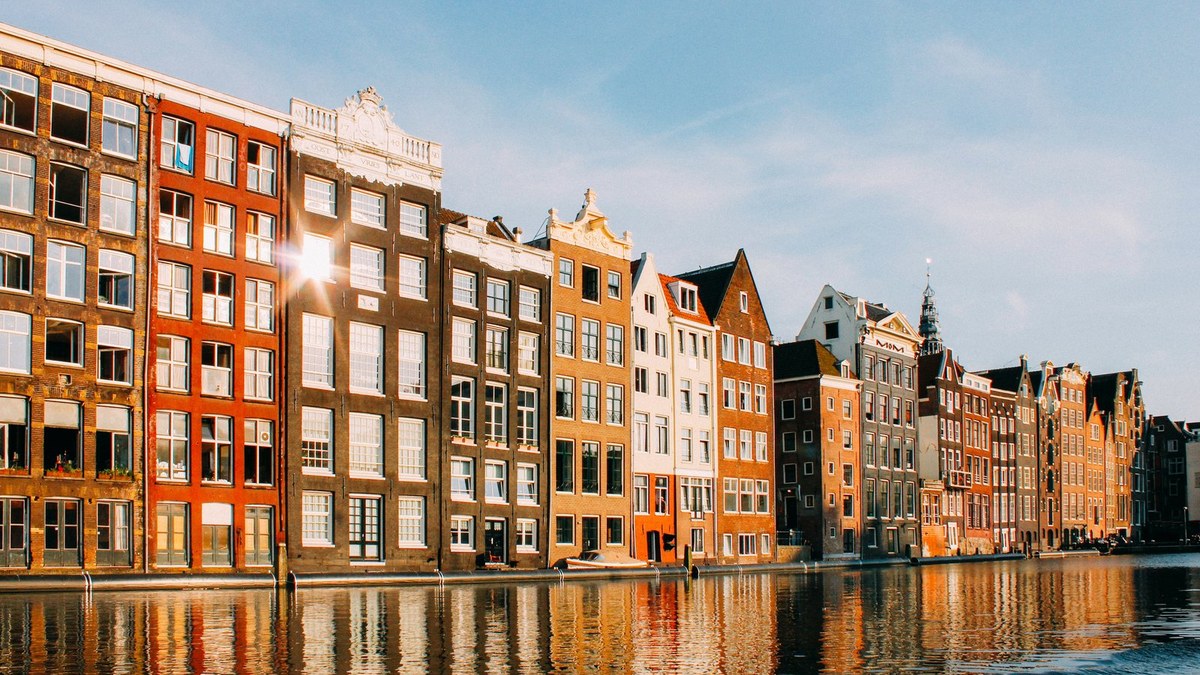 Façades colorées d'Amsterdam au bord d'un canal au coucher du soleil, ville où Tenways a installé son siège