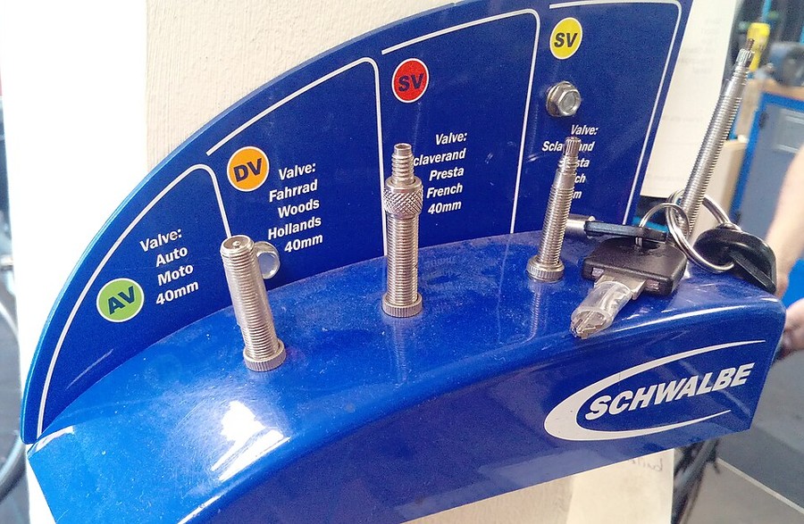Présentoir Schwalbe de trois types de valves de vélo : AV (Schrader), DV (Dunlop) et SV (Presta), avec leurs noms